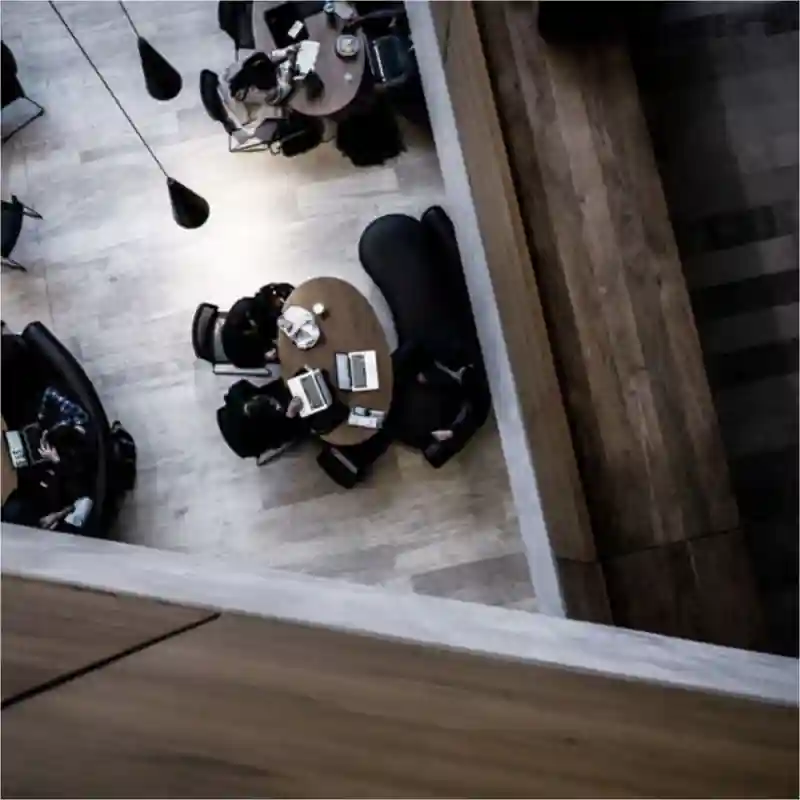 Aerial view of people sitting in a café, with laptops on tables, working.