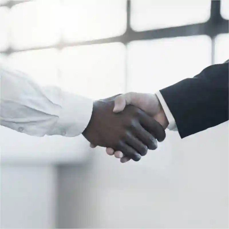 two people wearing business attire, shaking hands.