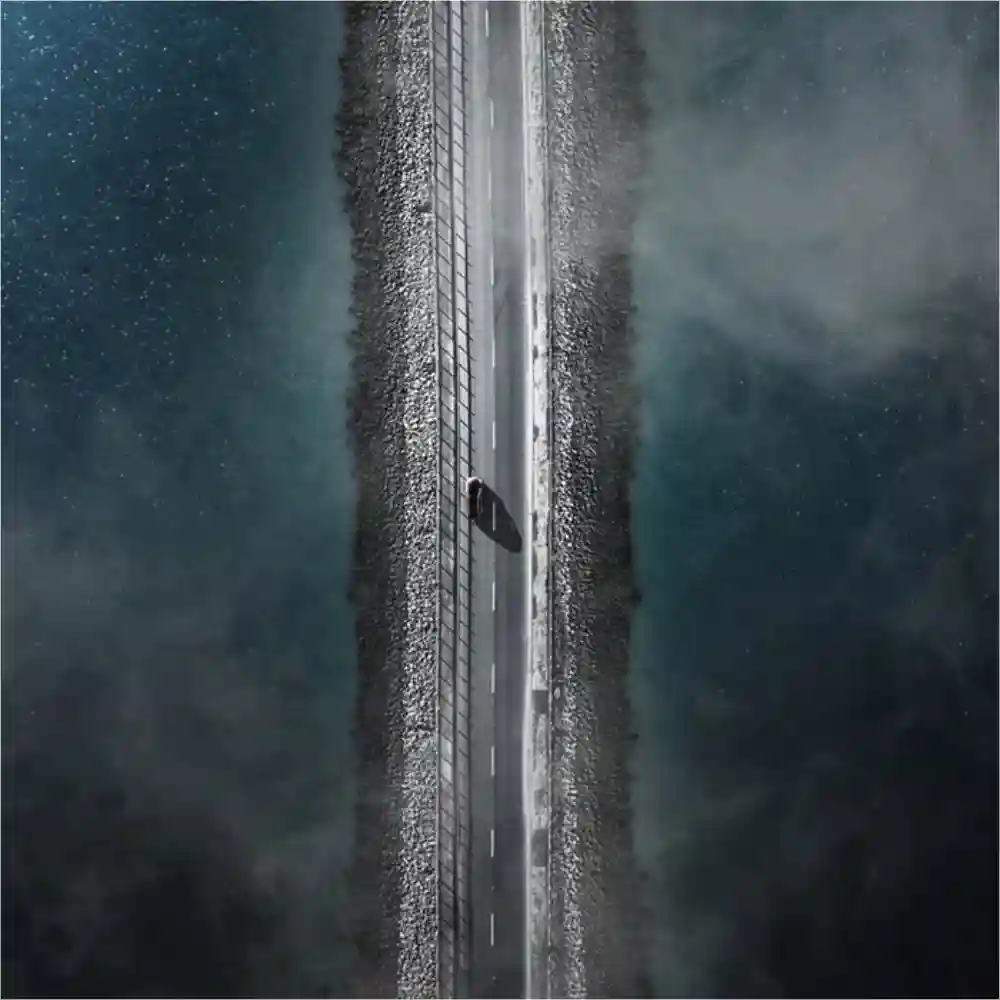 Aerial view of a car on a road with water on either side.