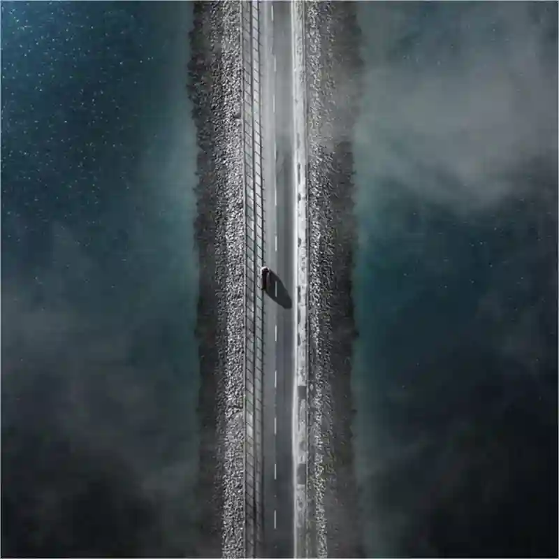 Aerial view of a car on a road with water on either side.