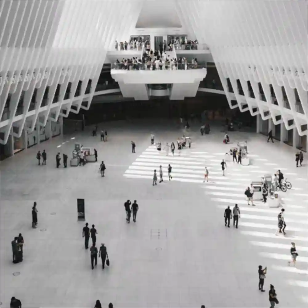 People walking inside a large white lobby.