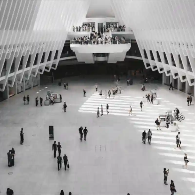 People walking inside a large white lobby.